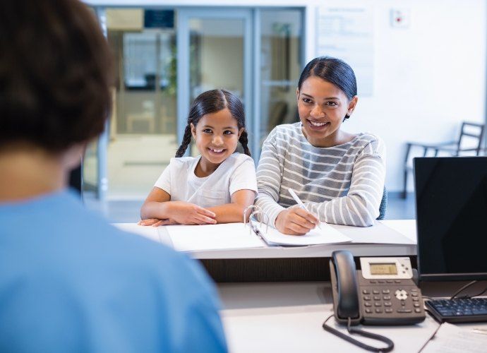 Mother and child discussing cost of treating dental emergencies with dental team member