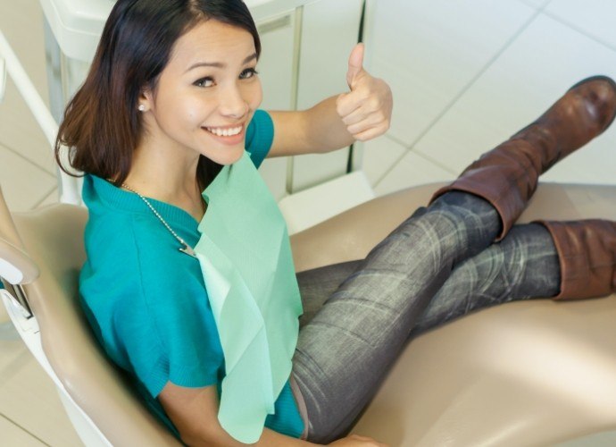 Patient giving thumbs up after preventive dentistry checkup and teeth cleaning