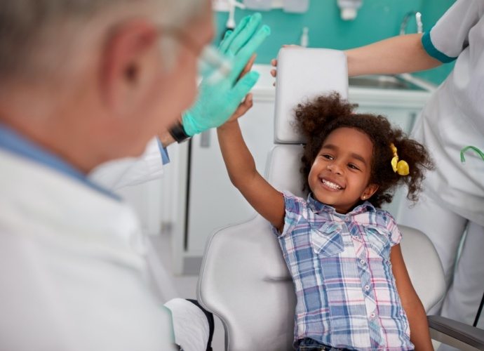 Child giving dentist a high five during children's dentistry visit