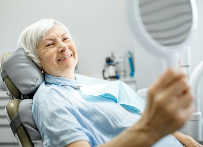 Woman looking at smile after dental implant process