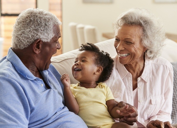 Older couple with grandchild enjoying the benefits of dental implants