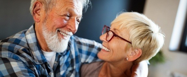 Man and woman smiling after replacing missing teeth with dental implants